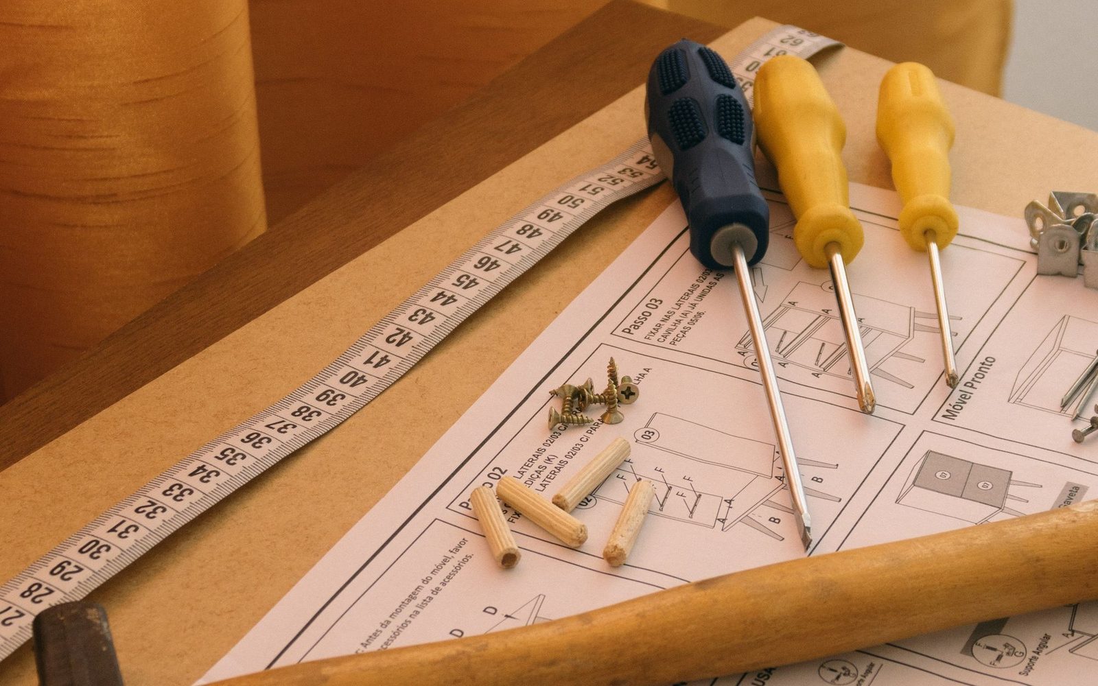 Flat pack furniture instructions with hammer and fixings laid out