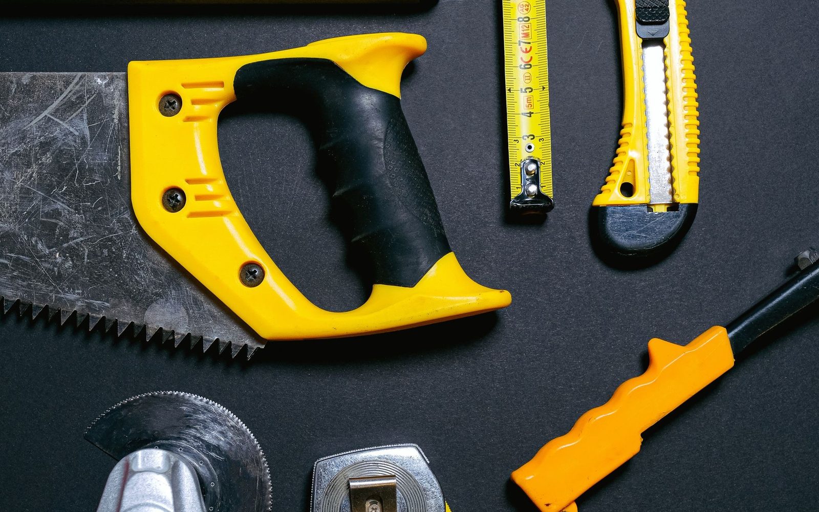 Hand tools arranged on a dark workbench