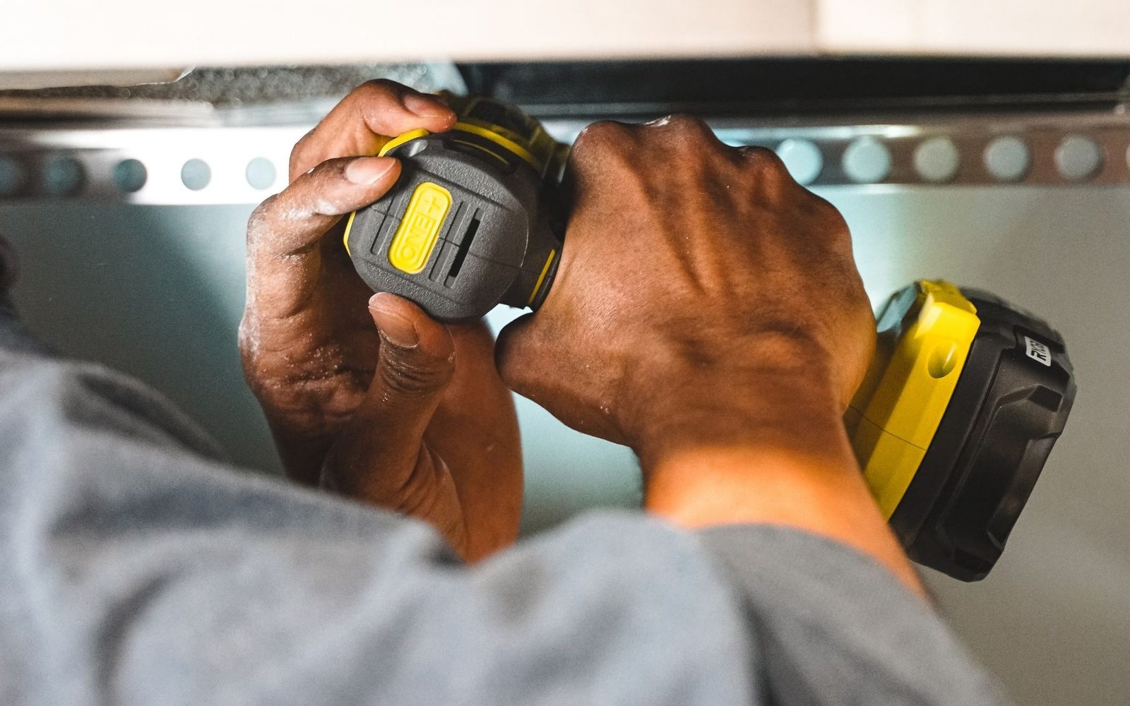Hands fixing a wall rail with a cordless drill