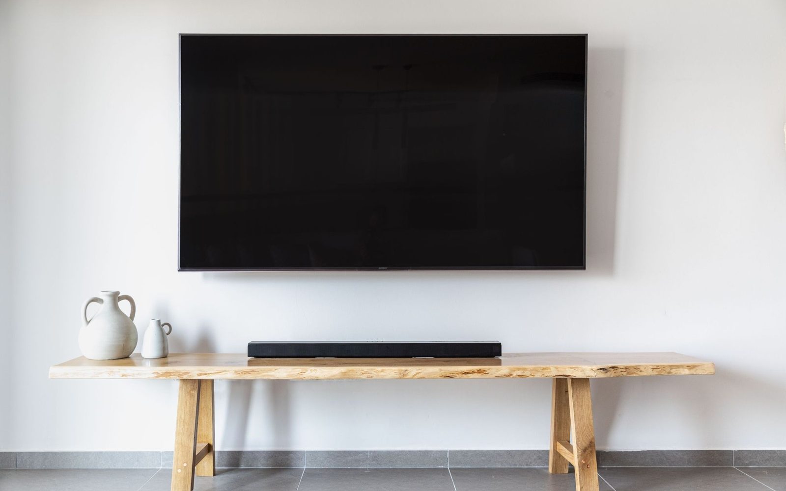Flat screen television wall-mounted above a wooden bench